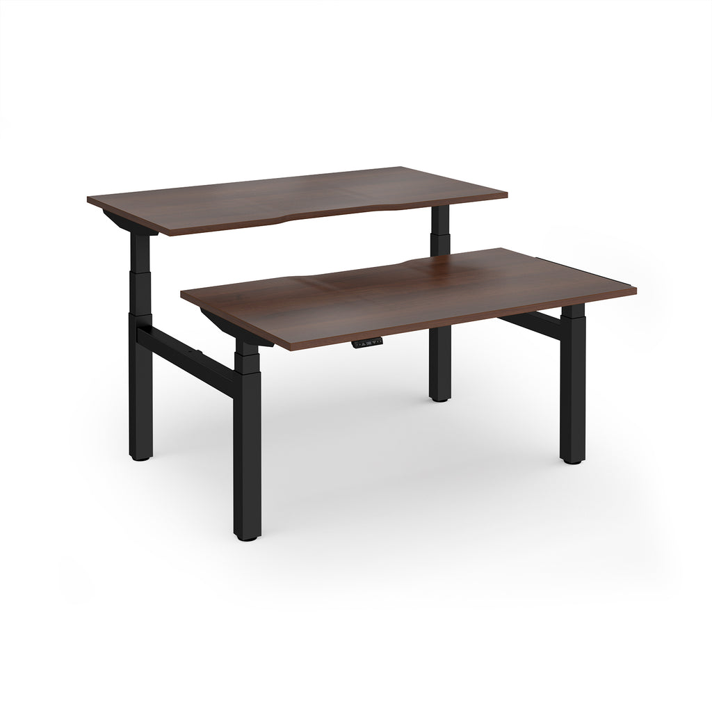 Two back-to-back height adjustable desks with shared black metal frame and wood-effect tops on a white background