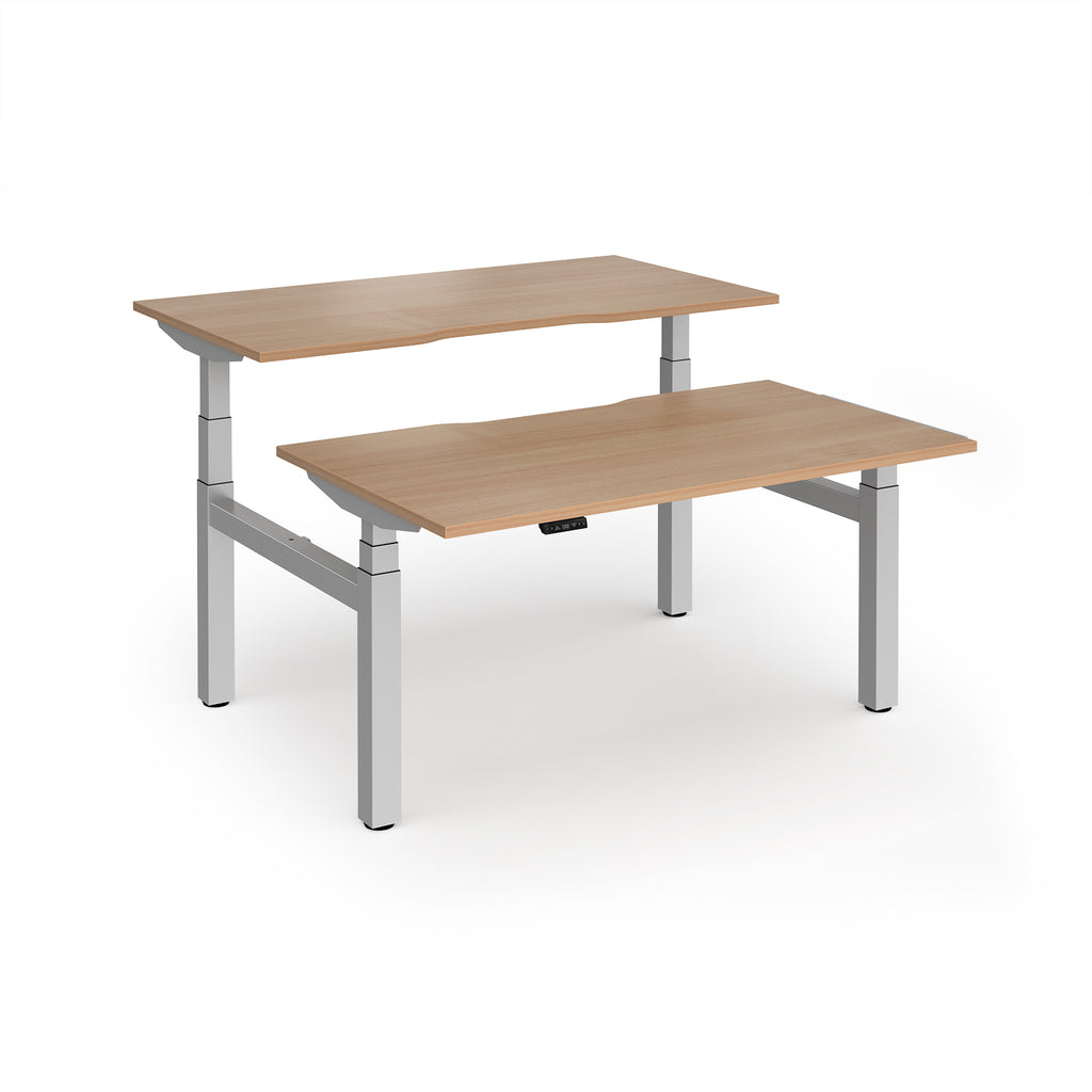 Two back-to-back height adjustable desks with shared silver metal frame and wood-effect tops on a white background