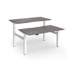Two back-to-back height adjustable desks with shared white metal frame and grey wood-effect tops on a white background