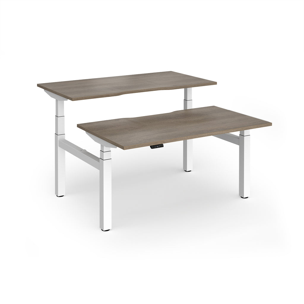 Two back-to-back height adjustable desks with shared white metal frame and wood-effect tops on a white background