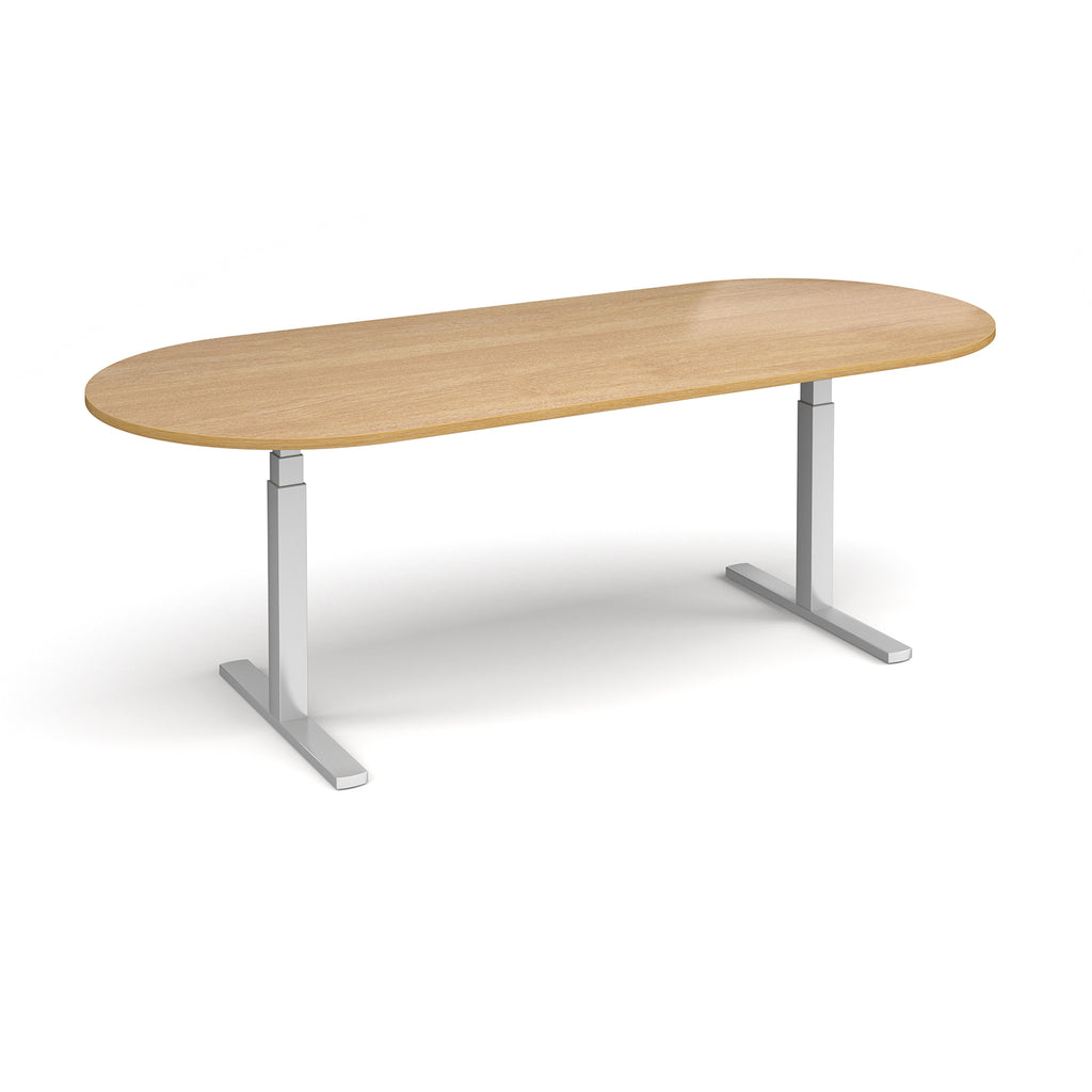 Oval height adjustable table with wood-effect top and silver metal frame on a white background