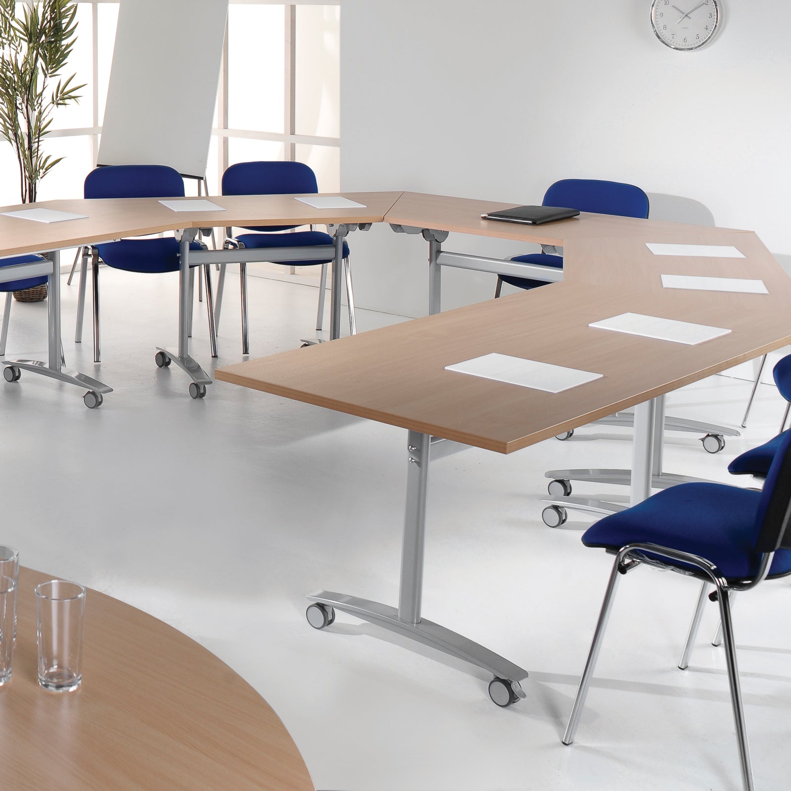 Modern conference room with hexagonal wooden tables and blue chairs.