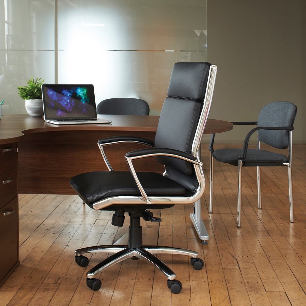 Modern office setup with a high-back chair, desk, and computer in a room with wooden flooring.