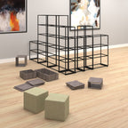 A modular black metal cube shelving system arranged in a room with light wood flooring, framed wall art, and several grey storage bins and olive-green fabric cube ottomans in the foreground.