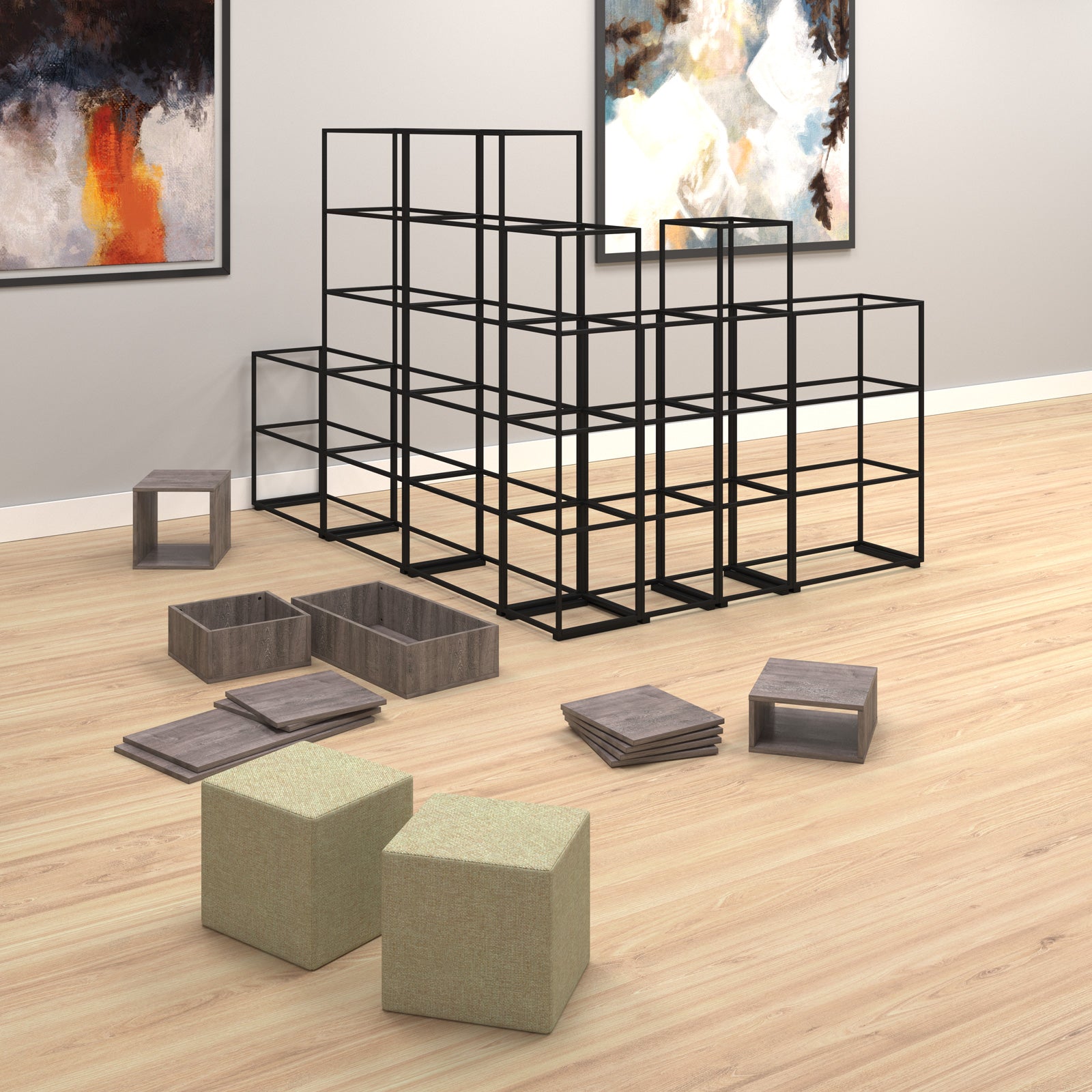 A modular black metal cube shelving system arranged in a room with light wood flooring, framed wall art, and several grey storage bins and olive-green fabric cube ottomans in the foreground.