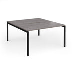 Office back-to-ack desk with grey wood-effect top and black metal frame on a white background