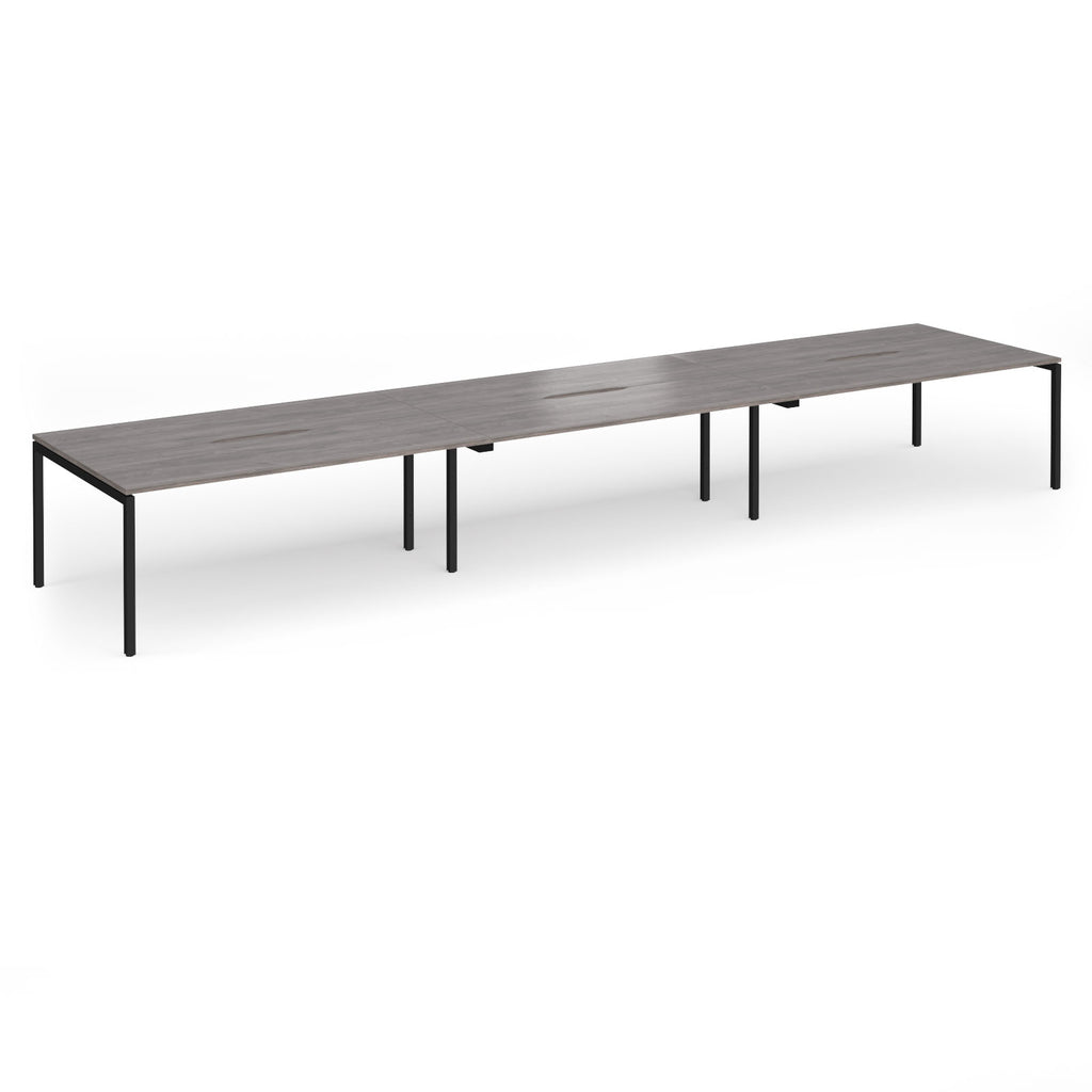 Triple back-to-back desk with grey wood-effect top and black legs on a white background