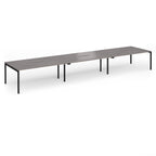 Triple back-to-back desk with grey wood-effect top and black legs on a white background
