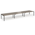 Triple back-to-back desk with wood-effect top and black legs on a white background