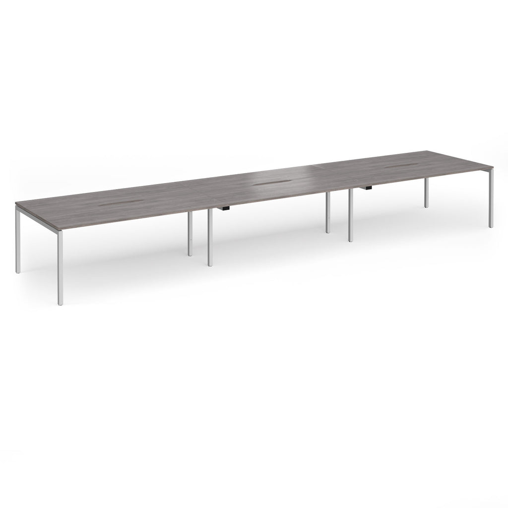 Triple back-to-back desk with grey wood-effect top and silver legs on a white background