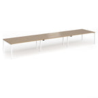 Triple back-to-back desk with wood-effect top and white legs on a white background