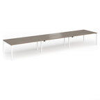 Triple back-to-back desk with wood-effect top and white legs on a white background