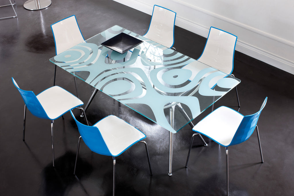Modern glass dining table with decorative pattern surrounded by chairs in a stylish interior setting.