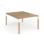 Back to back desk with light oak wood grain top and legs with white frame on a white background