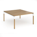 Back to back desk with light oak wood grain top and legs with white frame on a white background