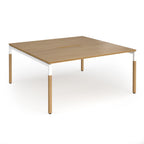 Back to back desk with light oak wood grain top and legs with white frame on a white background