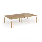 Double back to back desk with light oak wood grain top and legs with white frame on a white background
