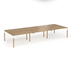 Triple back to back desk with light oak wood grain top and legs with white frame on a white background