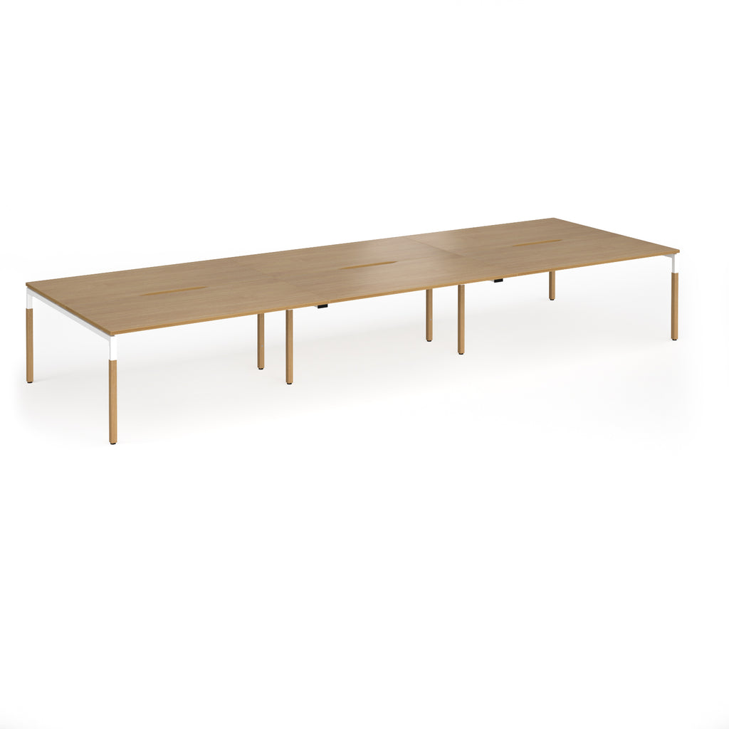 Triple back to back desk with light oak wood grain top and legs with white frame on a white background