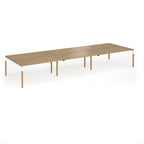 Triple back to back desk with light oak wood grain top and legs with white frame on a white background