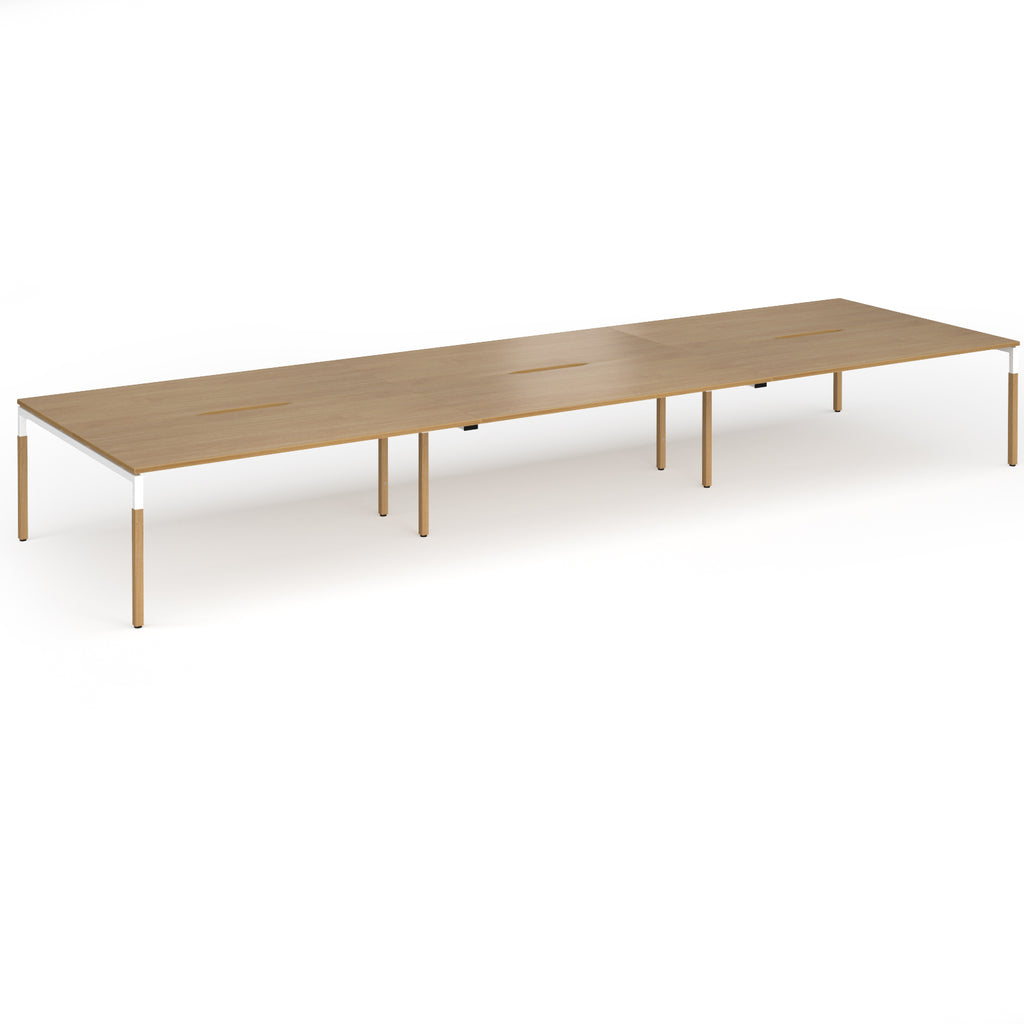 Triple back to back desk with light oak wood grain top and legs with white frame on a white background