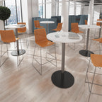 Modern office setting with high tables and orange chairs in a well-lit room.