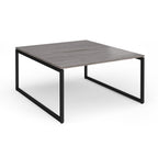 Back-to-back desk with grey wood-effect top and black metal legs on a white background