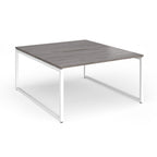 Back-to-back desk with grey wood-effect top and white metal legs on a white background