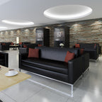 Modern lounge area with black leather couches and red pillows against a stone wall.
