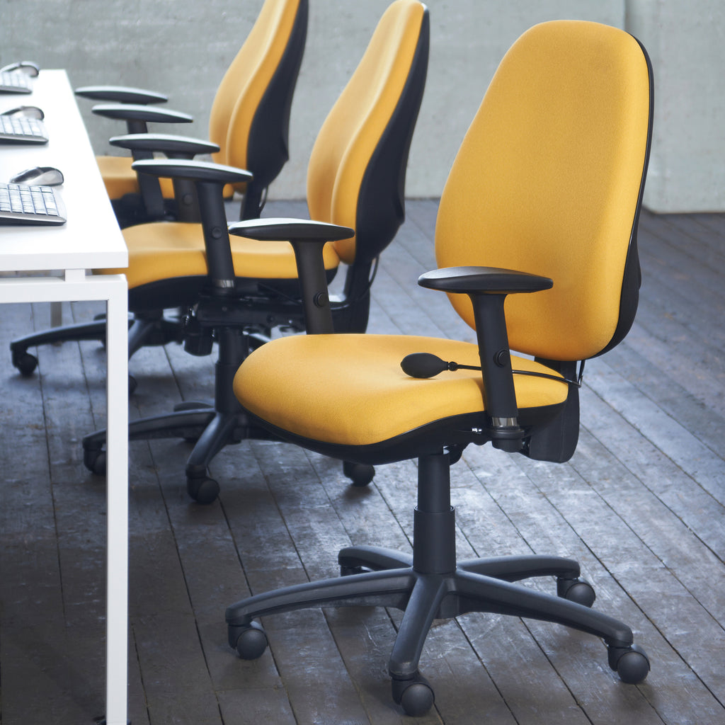 A row of modern office chairs with bright yellow upholstered seats and backs and black bases, armrests, and headrest supports, arranged in a room with dark wood flooring and a white desk on the left.