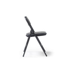 A black folding chair with a padded seat and curved backrest, shown from the side against a plain white background.