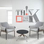 Two armchairs and a table with a wall with logo in the background