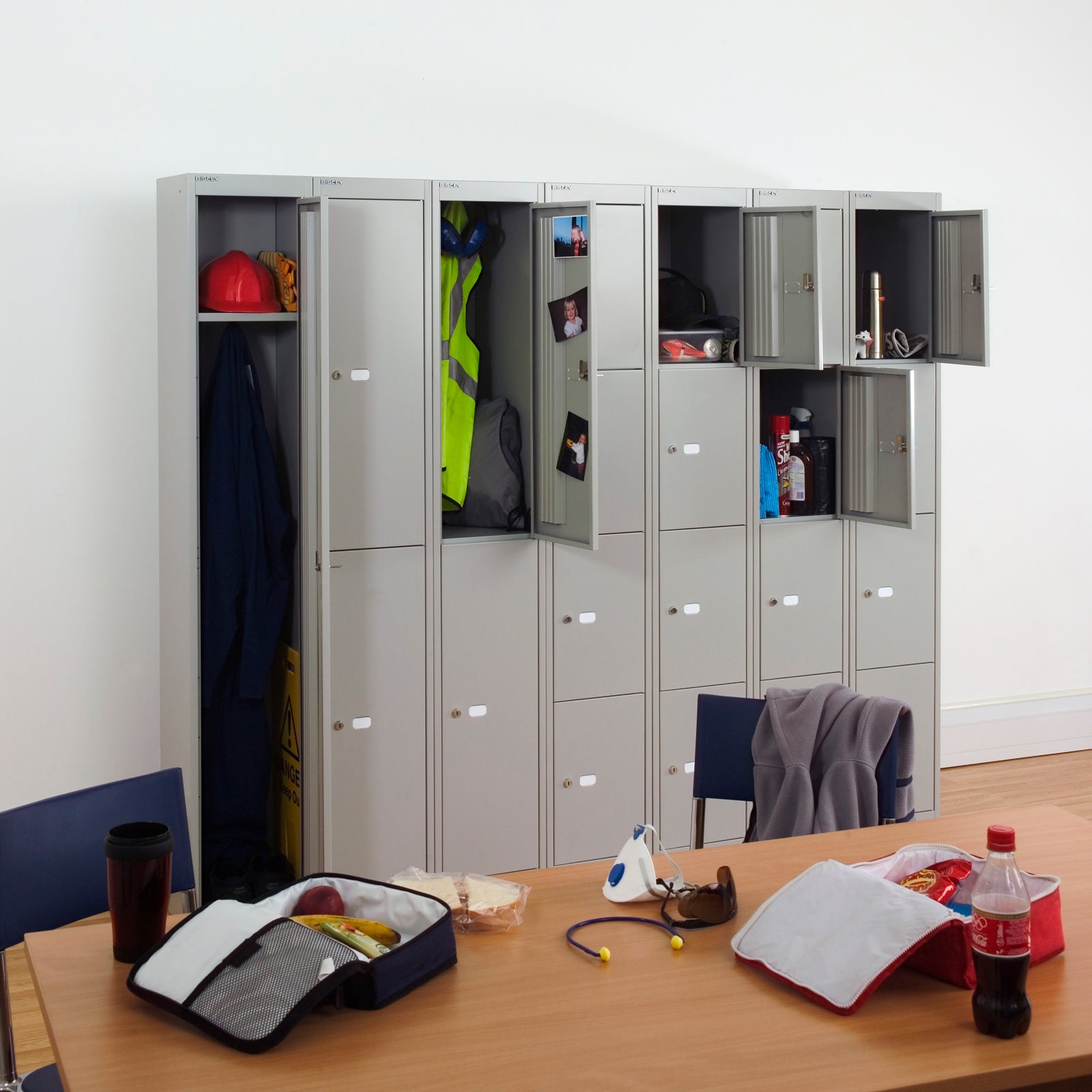 Row of grey lockers with items inside, a table with various objects in front