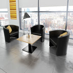Modern office waiting area with black armchairs and a wooden table.