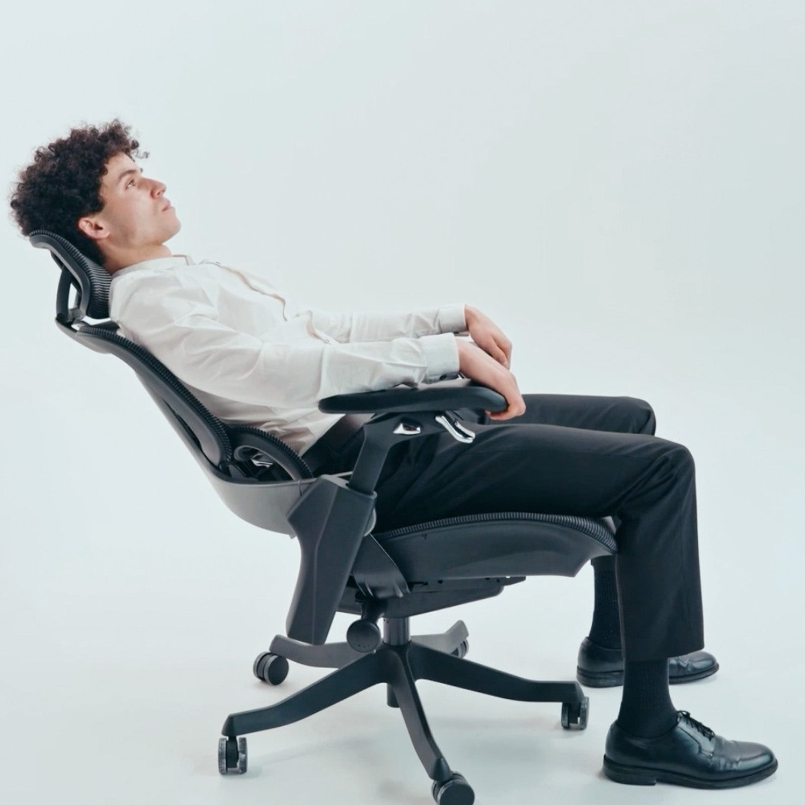 Person sitting on a black office chair with a white background