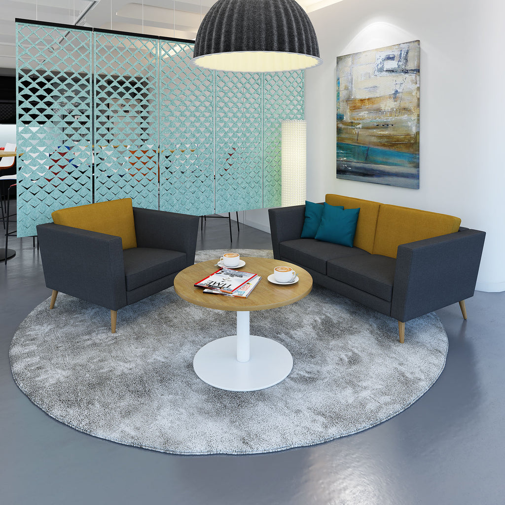 Breakroom setting with sofa, armchair and coffee table with painting and acoustic screen in the back