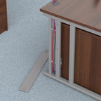 Wooden desk with exposed cables underneath on a light blue textured floor.