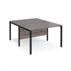 Back-to-back office desk with grey wood-effect top and black metal frame on a white background