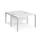 Back-to-back office desk with white top and silver metal frame on a white background