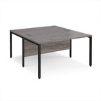 Back-to-back office desk with grey wood-effect top and black metal frame on a white background