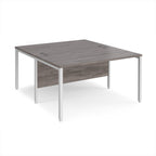 Back-to-back office desk with grey wood-effect top and white metal frame on a white background
