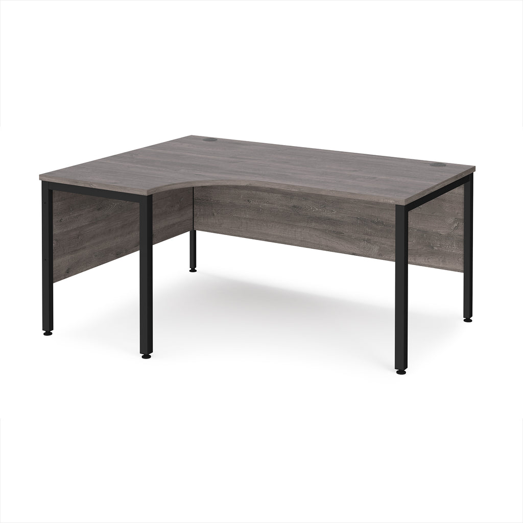 Ergonomic office desk with grey wood-effect top and black metal frame on a white background