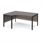 Ergonomic office desk with grey wood-effect top and black metal frame on a white background