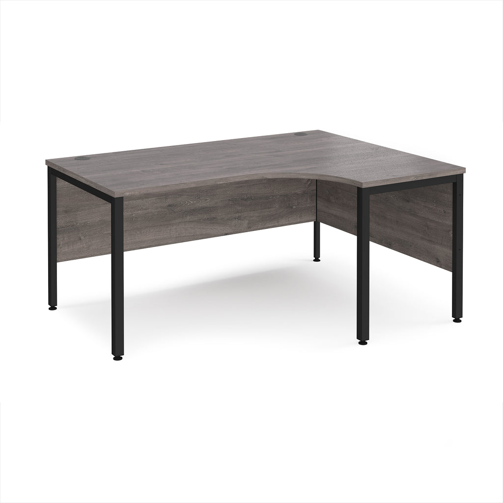 Ergonomic office desk with grey wood-effect top and black metal frame on a white background