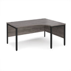 Ergonomic office desk with grey wood-effect top and black metal frame on a white background