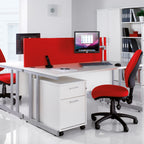 Modern office setup with red and white desks, chairs, and bookshelves.