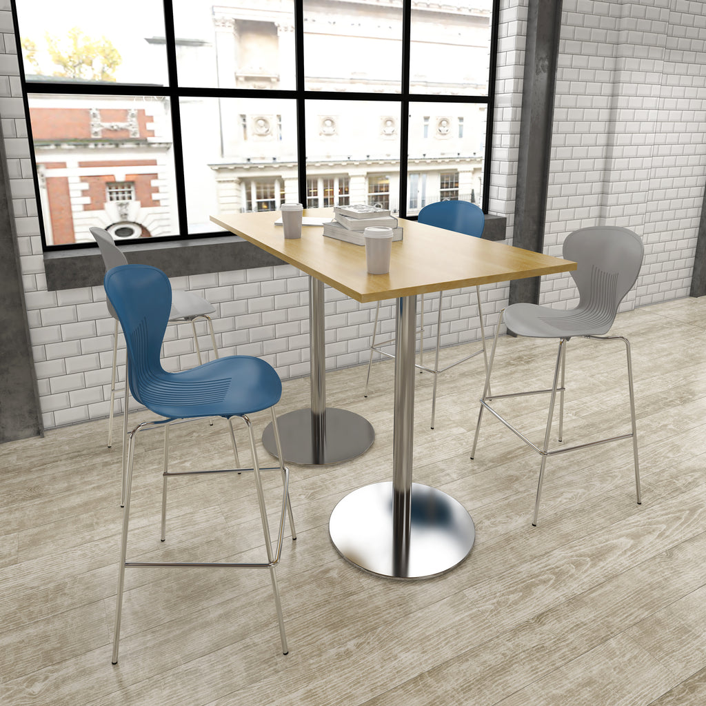 Modern cafe interior with a wooden table and colorful chairs against a brick wall.