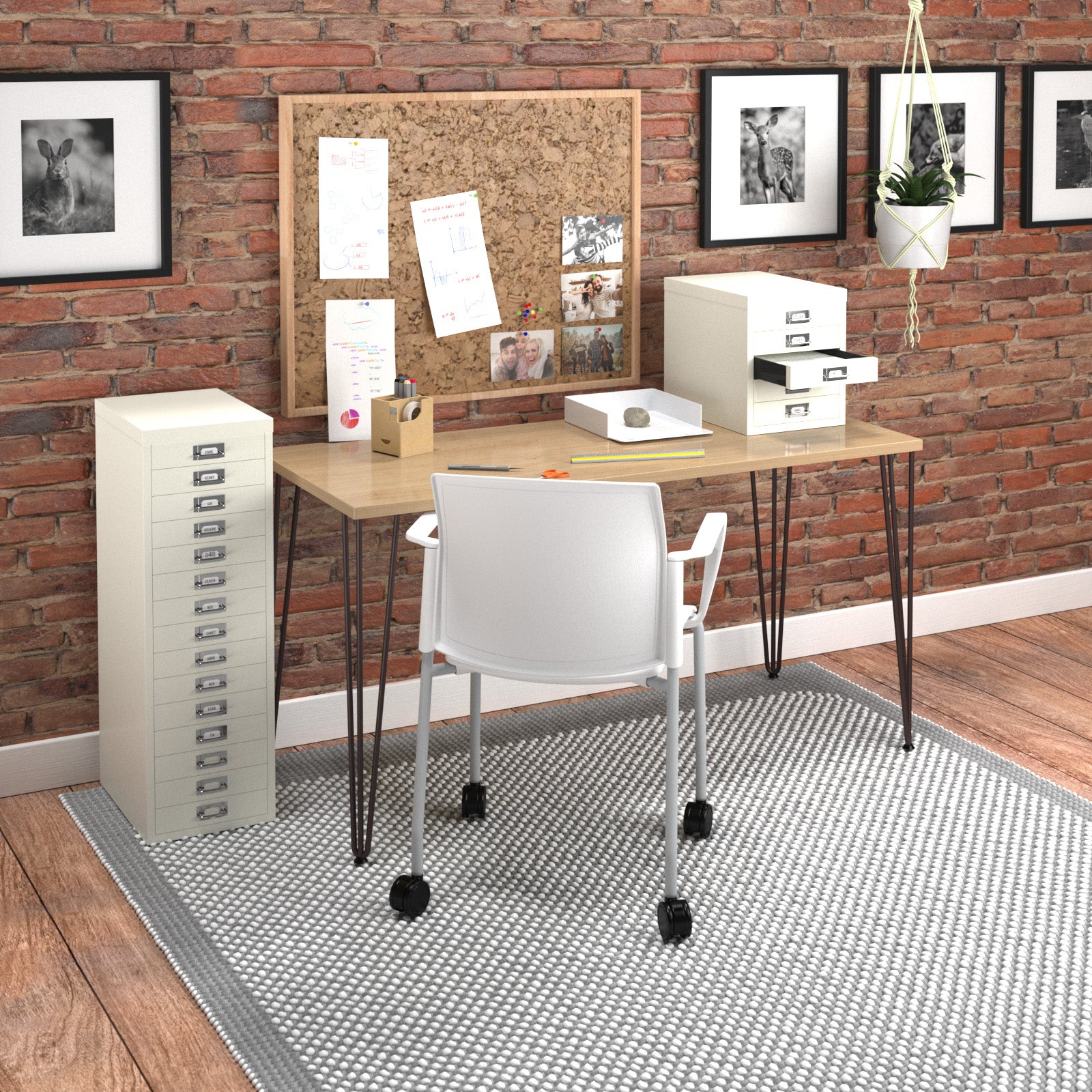 A white office chair with castors positioned in front of a light wood-top desk against a brick wall, with a cork board, filing cabinets, and framed wall art in a styled office setting.