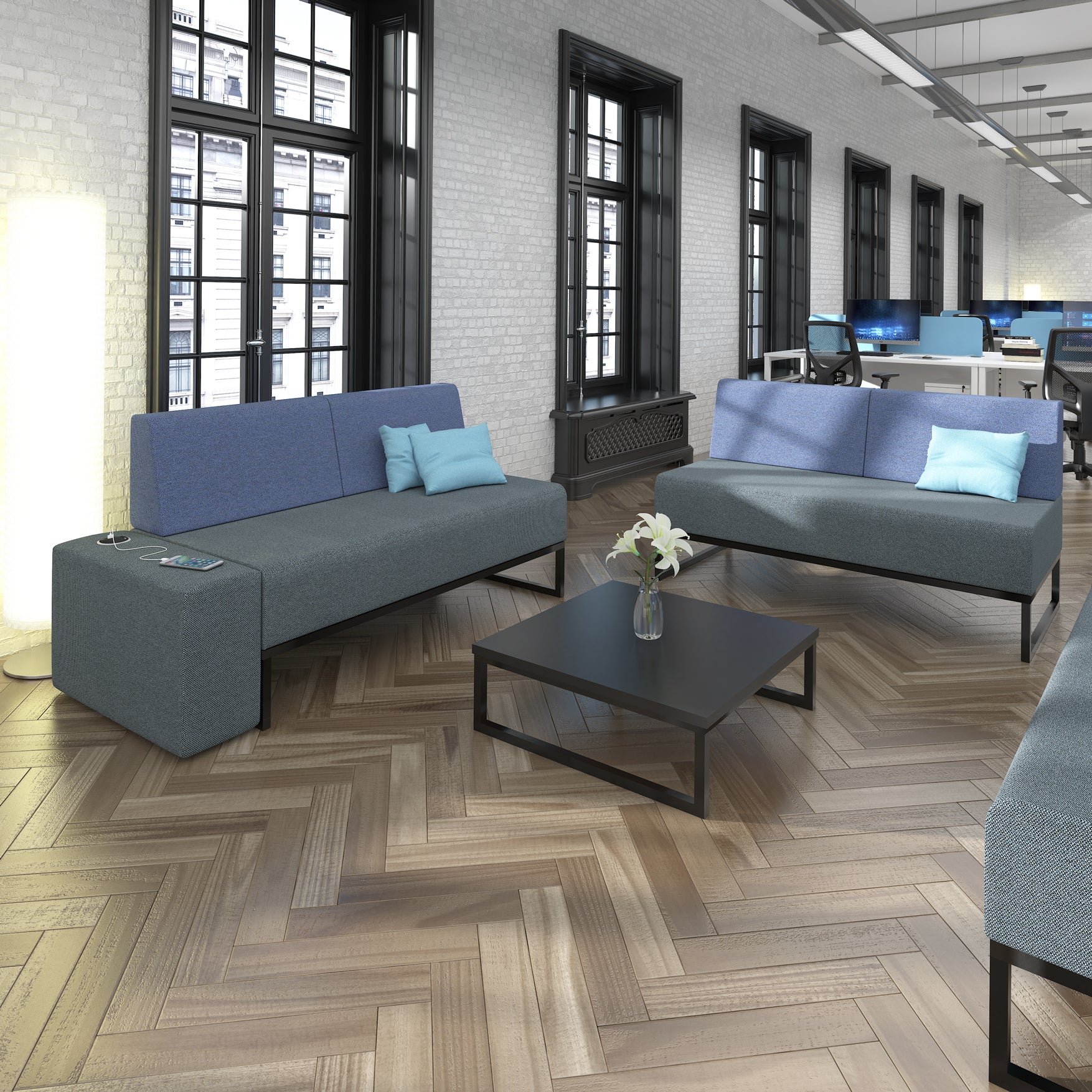 Modern office space with blue sofas, coffee table, and computer monitors.