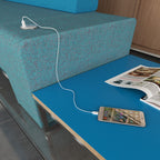 Blue table and sofa in an waiting room setting with power module and a phone on charge